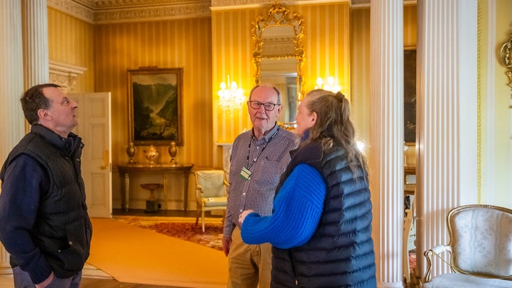 Volunteer room guide speaking to visitors at Hinton Ampner